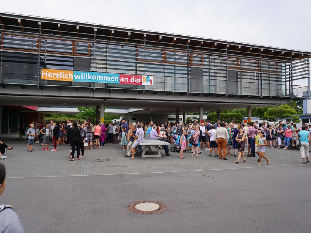 Banner „Herzlich willkommen an der“ über dem Eingang.